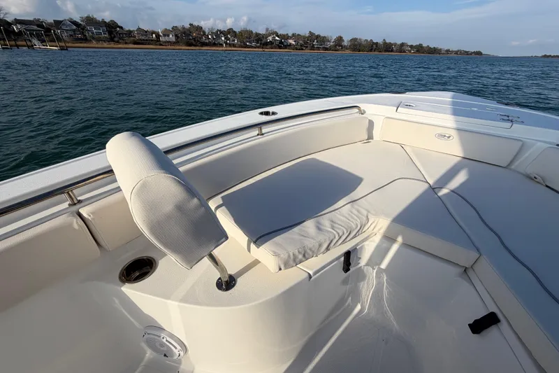 Slide: The Image of 2025 Sea Hunt Ultra 229 boat interior with cushioned seating, on calm water. - 18