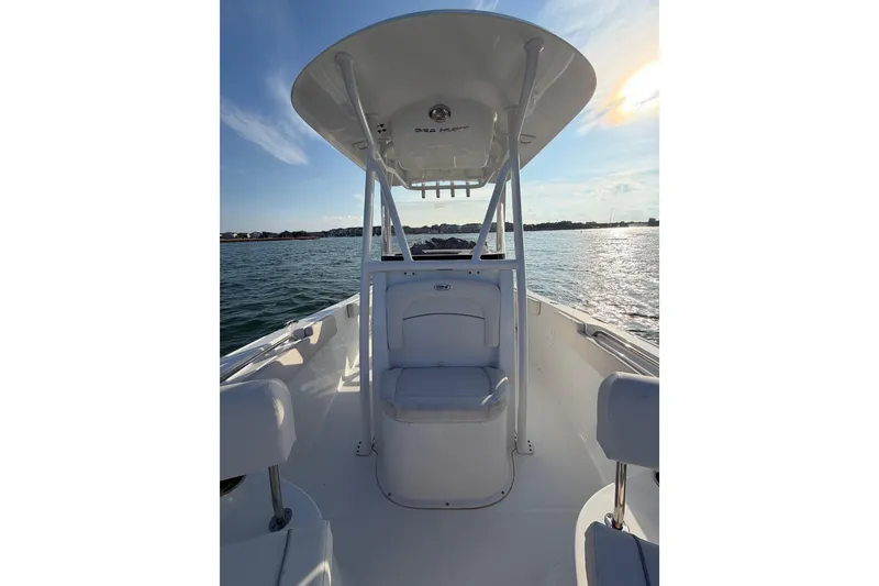 Slide: The Image of 2025 Sea Hunt Ultra 229 boat on water, featuring center console and seating, under sunny sky. - 23