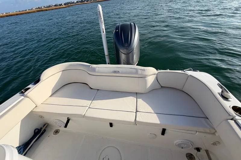 Slide: The Image of 2025 Sea Hunt Ultra 229 boat with cushioned seating and outboard motor on calm water. - 27