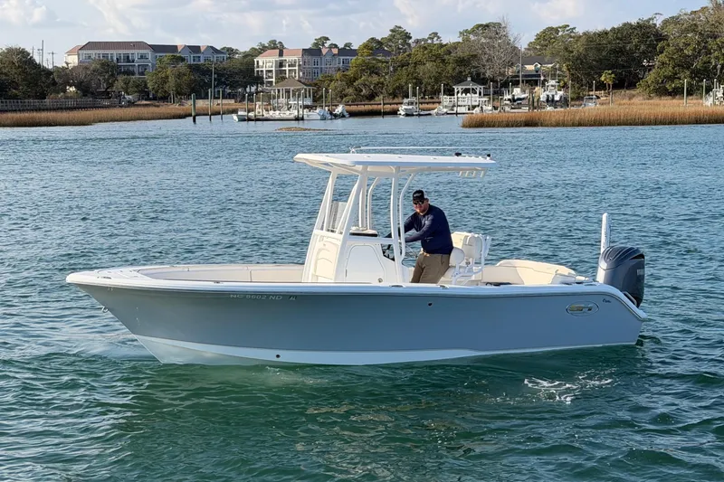 Slide: The Image of 2025 Sea Hunt Ultra 229 boat cruising on a scenic waterway with coastal backdrop. - 3