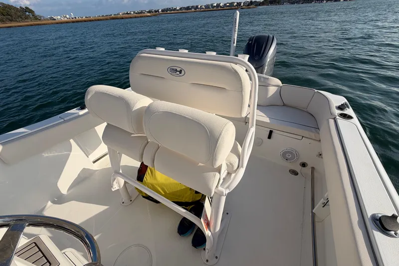 Slide: The Image of 2025 Sea Hunt Ultra 229 boat interior with cushioned seating on calm water. - 30