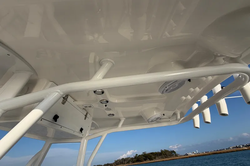 Slide: The Image of 2025 Sea Hunt Ultra 229 boat interior with rod holders and speakers, under clear blue sky. - 33