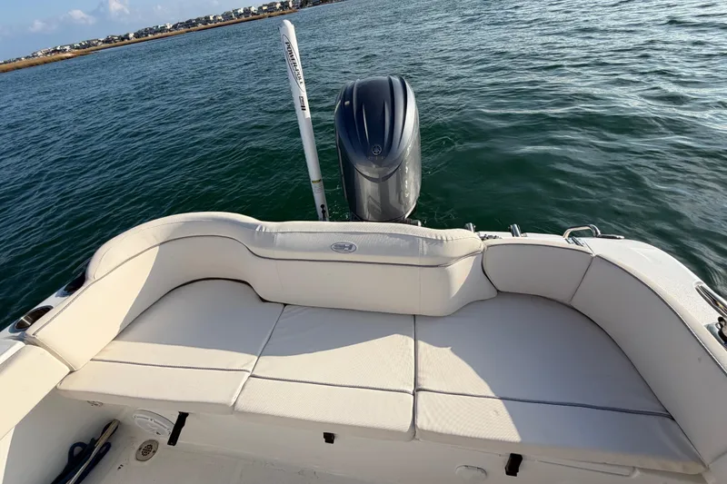 Slide: The Image of 2025 Sea Hunt Ultra 229 boat with cushioned seating and outboard motor on water. - 34