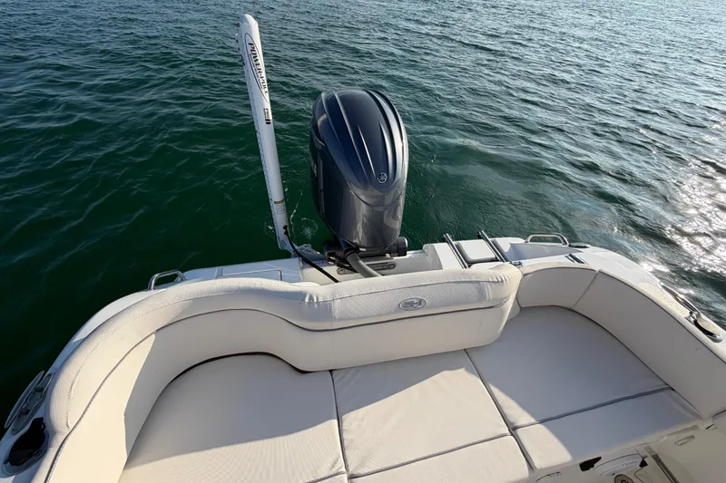 Slide: The Image of 2025 Sea Hunt Ultra 229 boat with cushioned seating and outboard motor on calm water. - 40