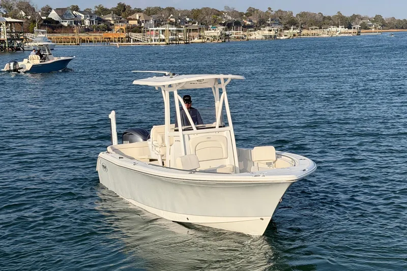 Slide: The Image of 2025 Sea Hunt Ultra 229 boat cruising on a calm coastal waterway. - 44