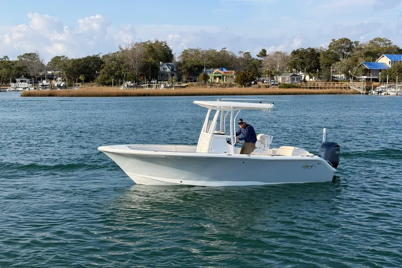 Slide: The Image of 2025 Sea Hunt Ultra 229 boat cruising on a calm lake with scenic shoreline. - 5