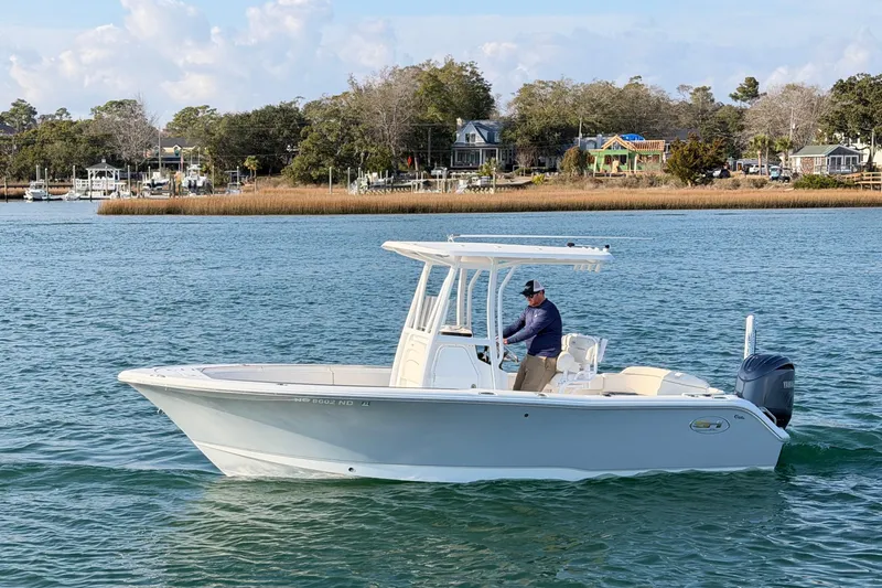 Slide: The Image of 2025 Sea Hunt Ultra 229 boat cruising on a scenic waterway with coastal homes in the background. - 8