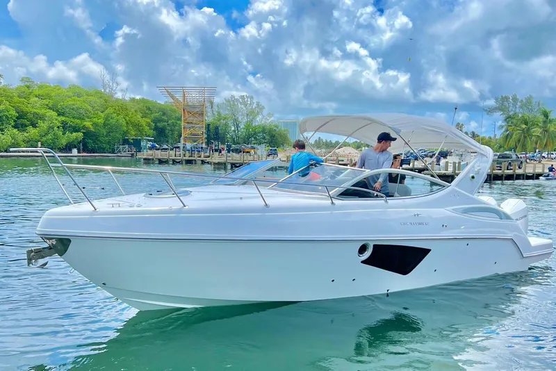 Slide: The Image of 2023 Schaefer 303 Sport boat cruising on a scenic waterway with lush greenery. - 2