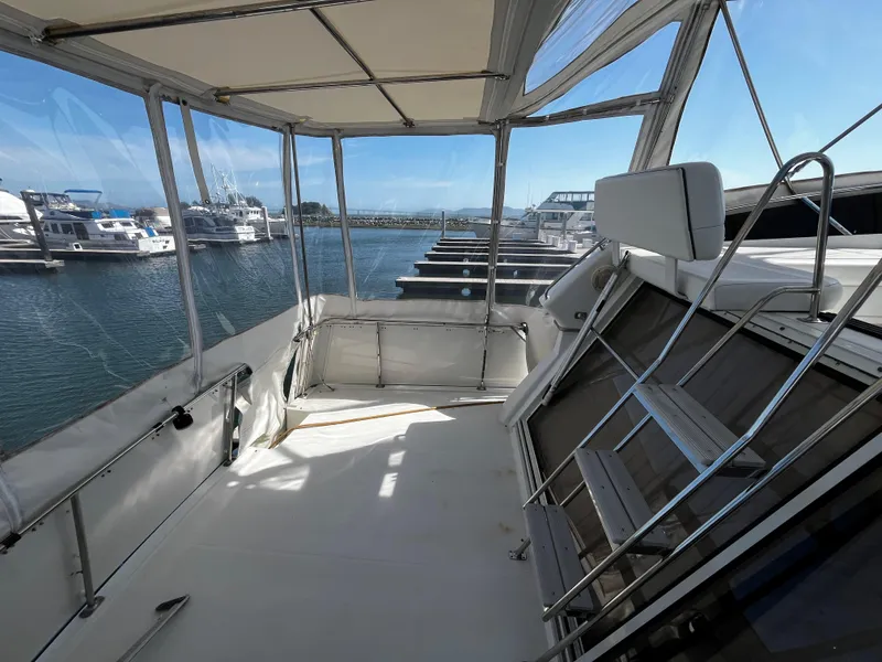 Slide: The Image of 1996 Carver 325 Aft Cabin boat interior with marina view, featuring enclosed deck and seating. - 11