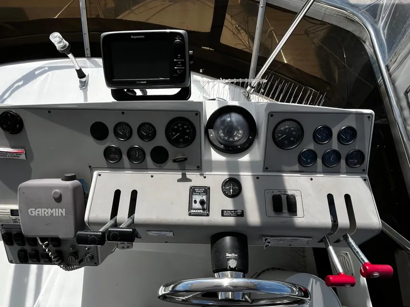 Slide: The Image of 1996 Carver 325 Aft Cabin helm with steering wheel and control panel, docked at marina. - 15