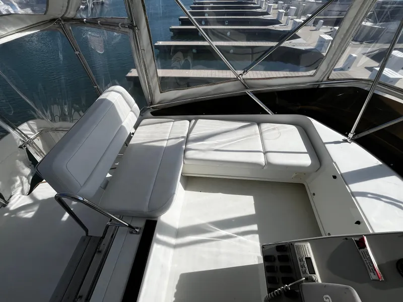 Slide: The Image of 1996 Carver 325 Aft Cabin yacht interior with white seating and marina view. - 18