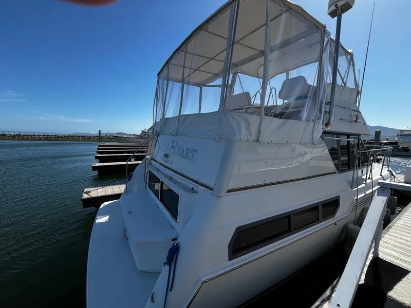 Slide: The Image of 1996 Carver 325 Aft Cabin yacht interior with marina view, featuring clear skies and docked boats. - 9