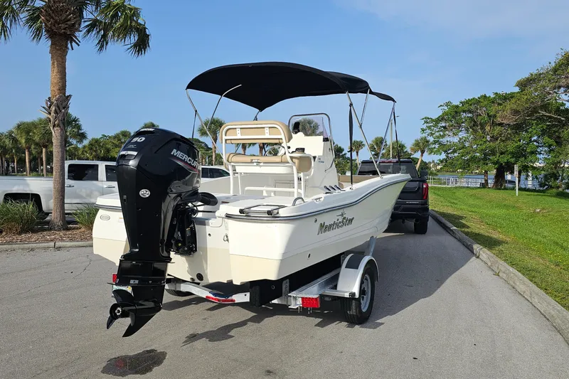 Slide: The Image of 2021 NauticStar 191 Hybrid boat on trailer, parked near palm trees and greenery. - 4