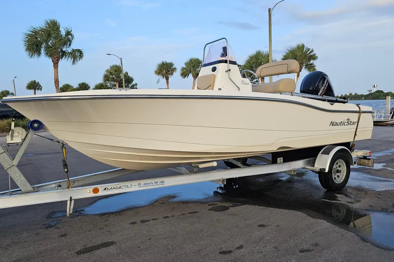 Slide: The Image of 2021 NauticStar 191 Hybrid boat on trailer, parked near palm trees and water. - 44