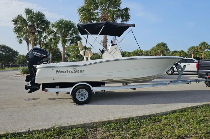 Slide: The Image of 2021 NauticStar 191 Hybrid boat on trailer, parked near palm trees. - 5