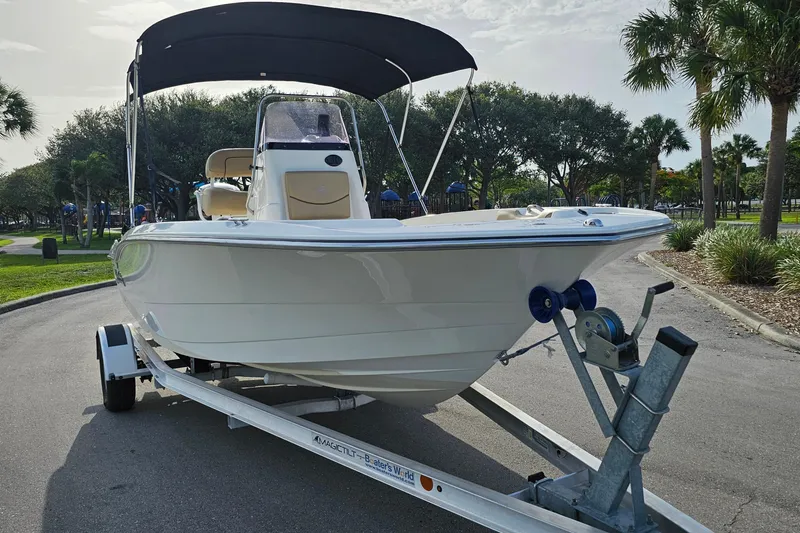 Slide: The Image of 2021 NauticStar 191 Hybrid boat on trailer, parked in a scenic area with trees. - 6