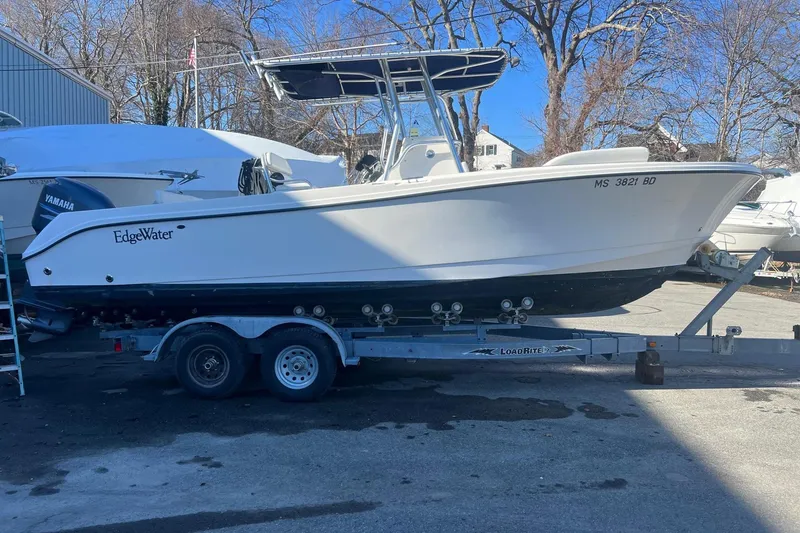 The Image of 2005 Edgewater 245CC boat on trailer, parked outdoors under clear blue sky. - 0