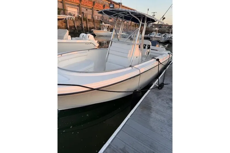 Slide: The Image of 2005 Edgewater 245CC boat docked at marina, featuring sleek white design. - 2