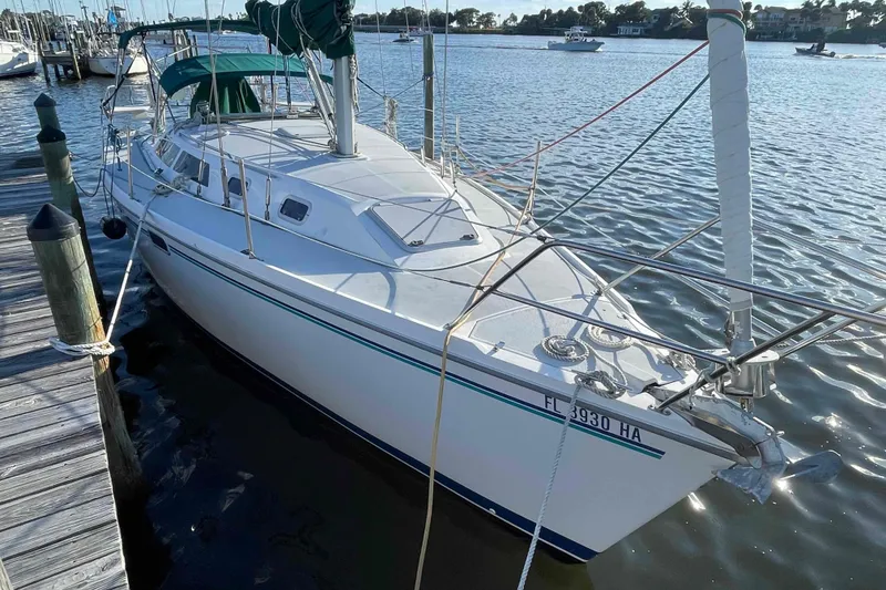 Slide: The Image of Catalina 320 sailboat from 1995 being lifted by a boat hoist at a marina. - 48