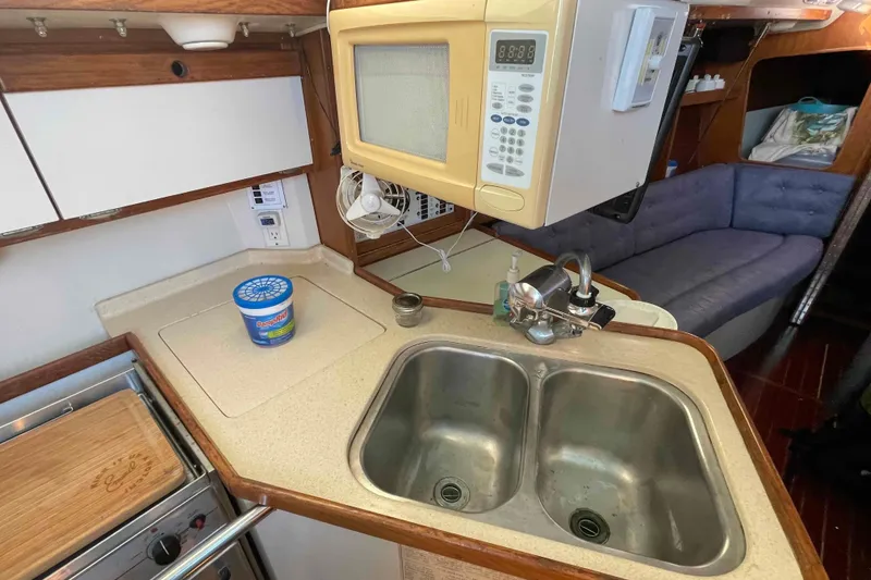 Slide: The Image of Catalina 320 sailboat cockpit with green cushions and canopy, docked by the water. - 74