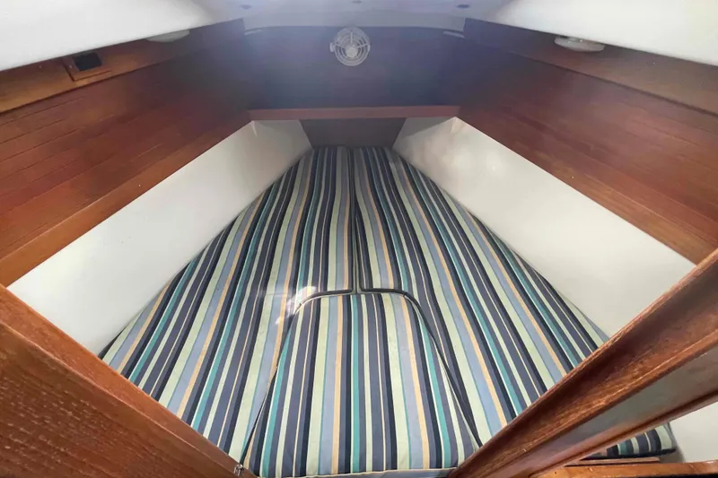 Slide: The Image of Interior of Catalina 320 sailboat with striped bedding and wooden cabinetry. - 91