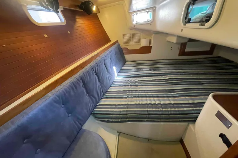 Slide: The Image of Cozy cabin interior of 1995 Catalina 320 sailboat with striped bedding and wooden accents. - 99