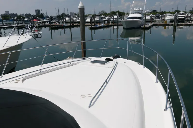 Slide: The Image of 2004 Sea Ray 480 Sedan Bridge yacht docked at a marina, surrounded by calm waters. - 12