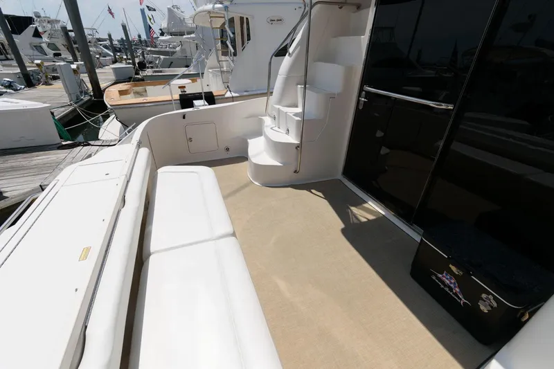 Slide: The Image of 2004 Sea Ray 480 Sedan Bridge yacht deck with seating and stairs, docked at marina. - 3