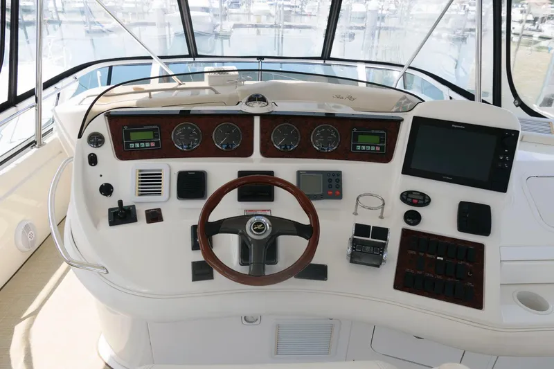 Slide: The Image of 2004 Sea Ray 480 Sedan Bridge helm with gauges, steering wheel, and navigation controls. - 9