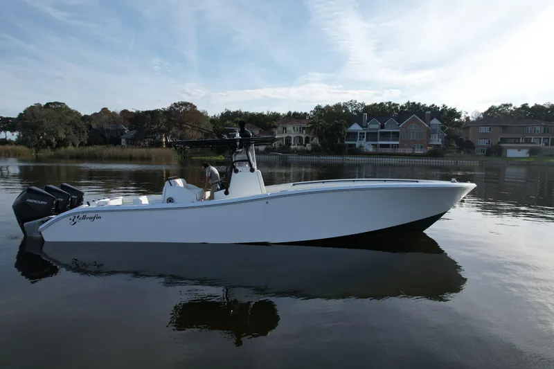 Slide: The Image of 2009 Yellowfin 36 Offshore boat on calm water, with houses in the background. - 15