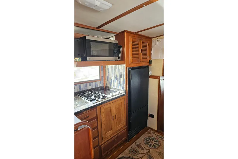 Slide: The Image of 1984 Albin Palm Beach 37 yacht kitchen with stove, microwave, and wooden cabinetry. - 36