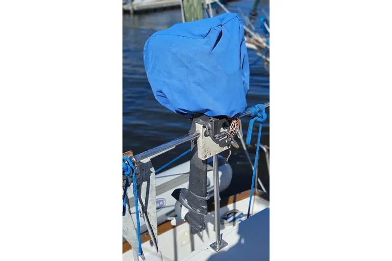 Slide: The Image of Blue-covered outboard motor on 1984 Albin Palm Beach 37 boat, docked by water. - 60