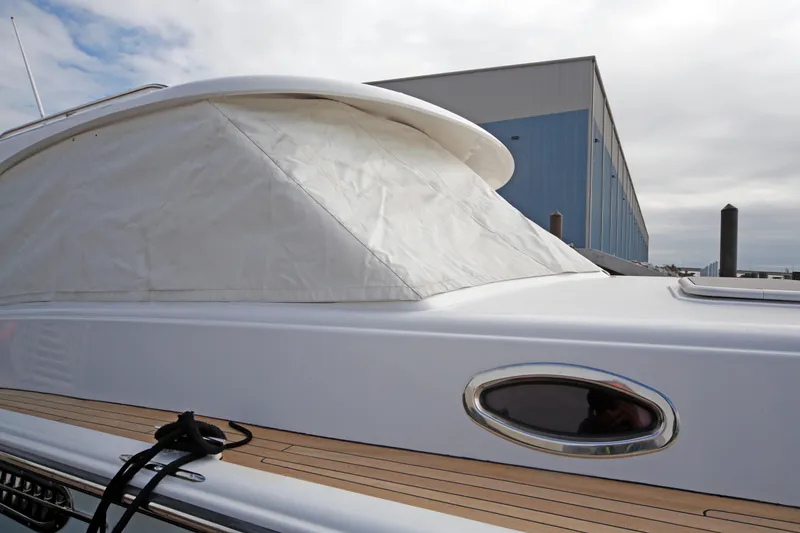 Slide: The Image of San Juan 41 yacht, 2014 model, with white cover and wooden deck, docked near a blue building. - 8