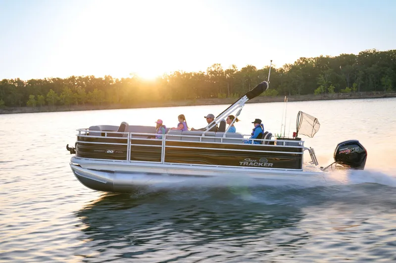 Slide: The Image of 2026 Sun Tracker SportFish 20 DLX pontoon boat with seating and canopy, docked outdoors. - 2