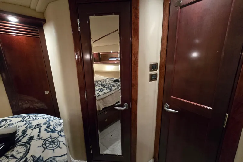 Slide: The Image of 2007 Sea Ray 52 Sedan Bridge cabin with open closet and nautical-themed bedding. - 53