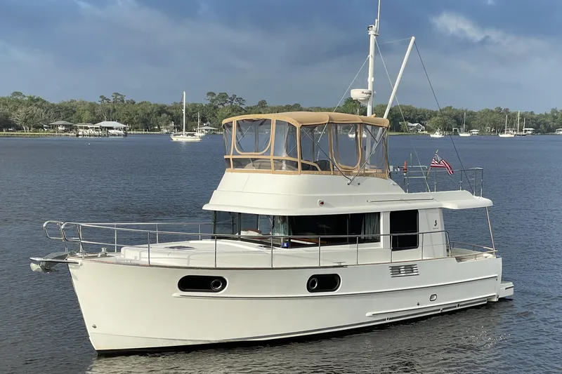 The Image of 2013 Beneteau Swift Trawler 44 cruising on a calm river under a cloudy sky. - 0