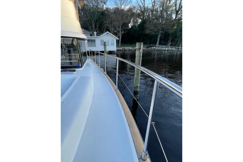 Slide: The Image of 2013 Beneteau Swift Trawler 44 docked by a serene waterfront house. - 10