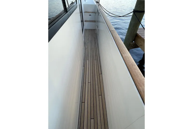 Slide: The Image of 2013 Beneteau Swift Trawler 44 side deck with wooden flooring, docked by water. - 11