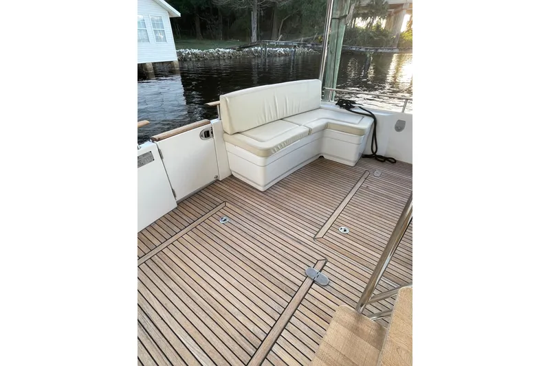 Slide: The Image of 2013 Beneteau Swift Trawler 44 deck with cushioned seating and wooden flooring. - 14