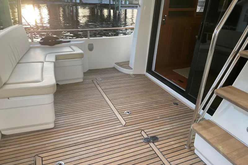 Slide: The Image of 2013 Beneteau Swift Trawler 44 deck with seating, wooden flooring, and stairs. - 16