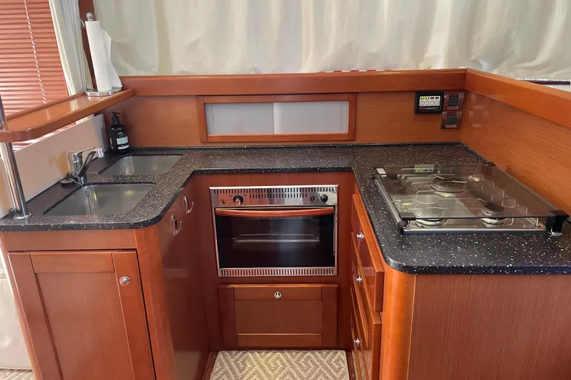 Slide: The Image of 2013 Beneteau Swift Trawler 44 kitchen with wood cabinetry, dual sink, stove, and oven. - 24