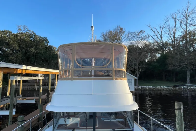 Slide: The Image of 2013 Beneteau Swift Trawler 44 docked by a serene riverside setting. - 7