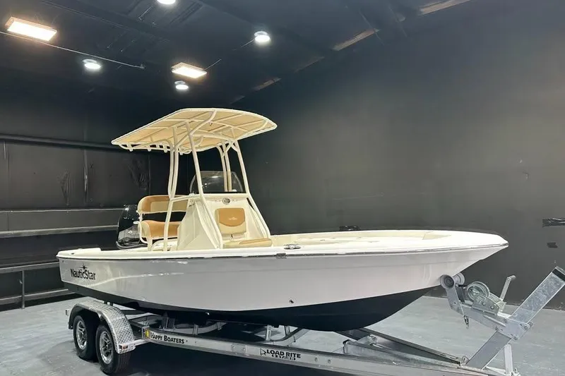 The Image of 2023 NauticStar 215 XTS boat on trailer in showroom setting. - 0