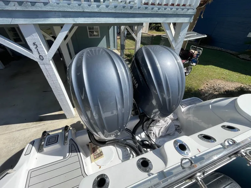 Slide: The Image of 2024 Sea Fox 288 Commander with dual outboard engines, parked under a wooden structure. - 48