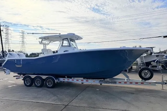Slide: The Image of 2026 Tidewater 320 CC Adventure boat on a trailer, parked outdoors. - 2