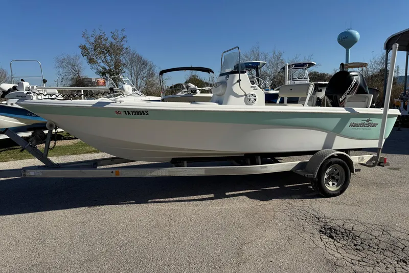Slide: The Image of 2015 NauticStar 1910 NauticBay boat on trailer, parked outdoors under clear sky. - 18