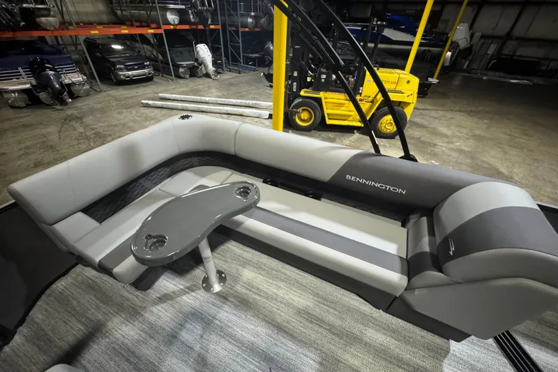 Slide: The Image of 2026 Bennington 20SL pontoon boat interior with gray seating and table in warehouse. - 17