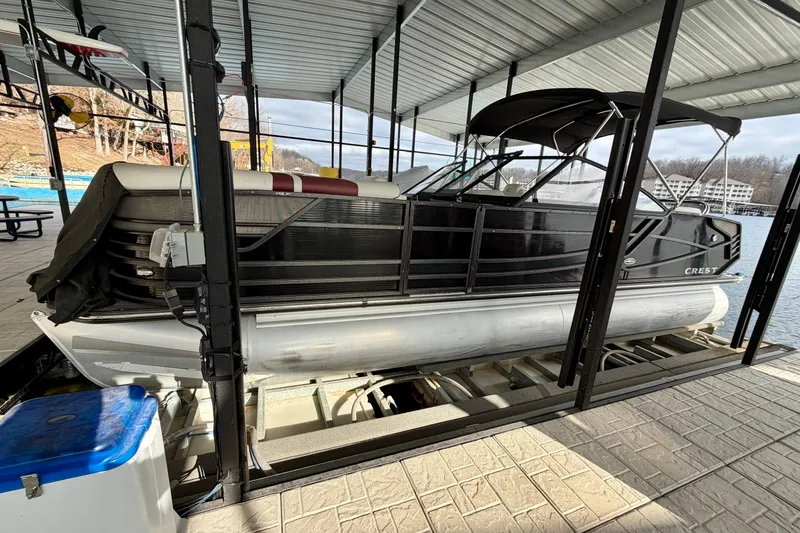 The Image of 2019 Crest Continental 250 SLS pontoon boat docked under a covered marina. - 0