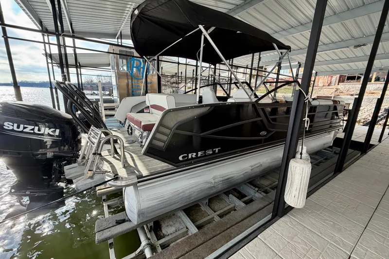 Slide: The Image of 2019 Crest Continental 250 SLS pontoon boat docked under a covered marina. - 2