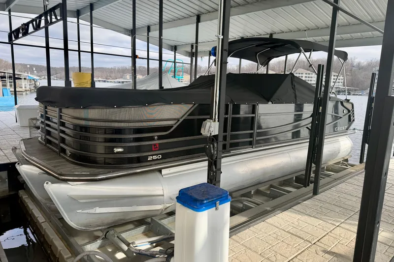 Slide: The Image of 2019 Crest Continental 250 SLS pontoon boat docked in a covered marina. - 5
